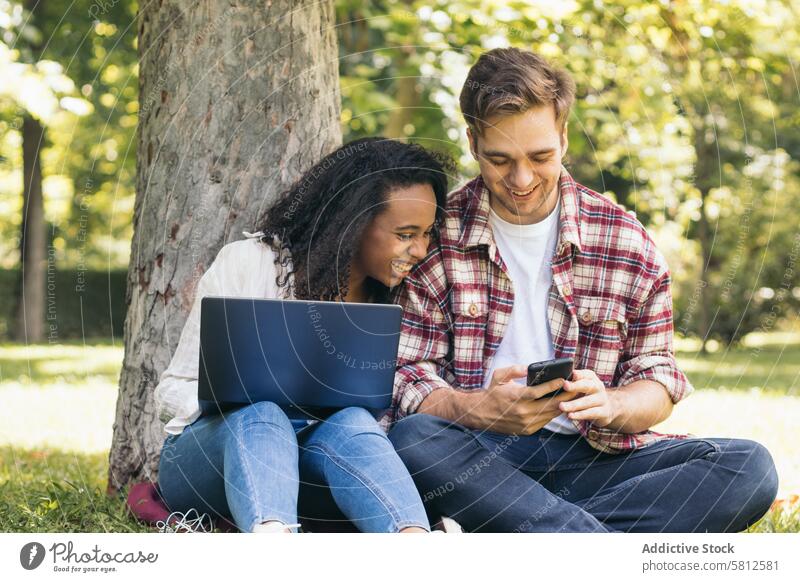 Multiracial couple studying in the park with laptop multiracial together people young woman working technology modern two learning students outdoors teamwork