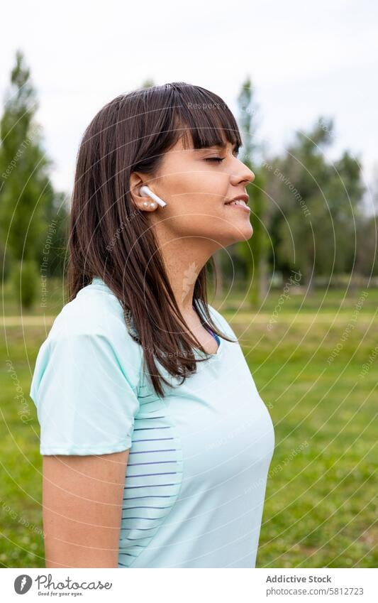 Runner woman relaxed listening to music for training outdoors active activewear adult athlete athletic body break breathing calm caucasian earphones energy