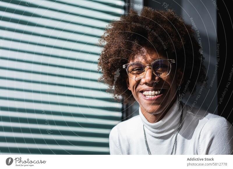 Content young African American guy smiling at camera man cheerful smile charismatic style portrait positive trendy appearance personality window jalousie male