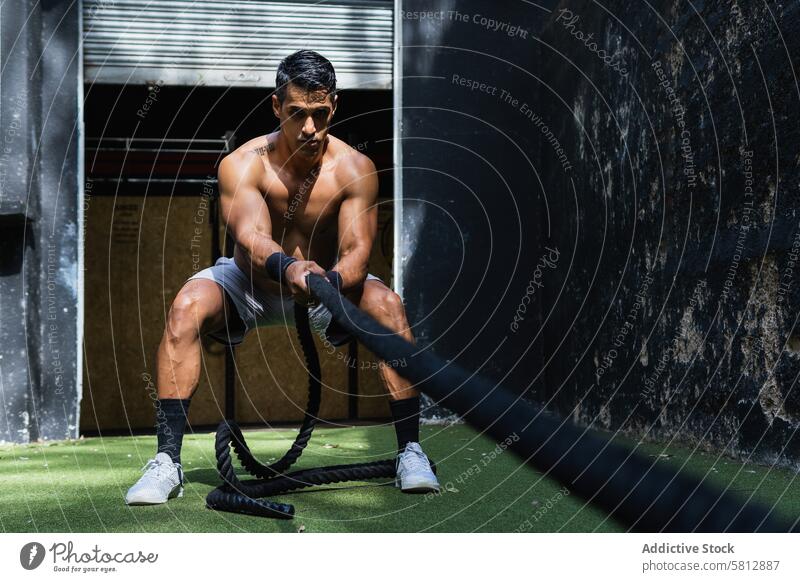 Muscular Hispanic sportsman pulling weight sled powerlifting training gym exercise workout sporty healthy lifestyle activewear sportswear wellness hispanic