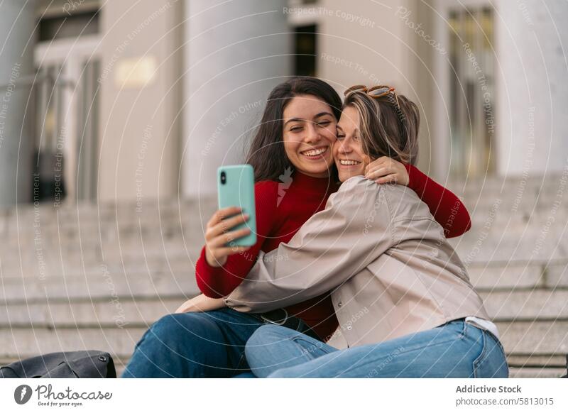 two student girls smiling taking a selfie sitting on the stairs of the college. lifestyle happiness female women young vacation friends youth smile leisure
