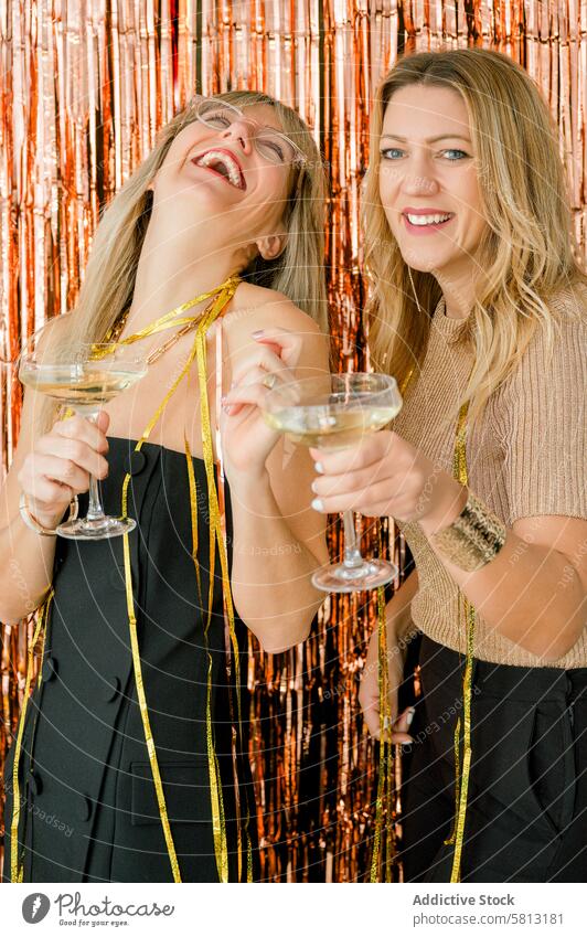 Cheerful women with champagne celebrating New Year alcohol glass tinsel drink beverage celebrate party style holiday female woman festive luxury cheerful