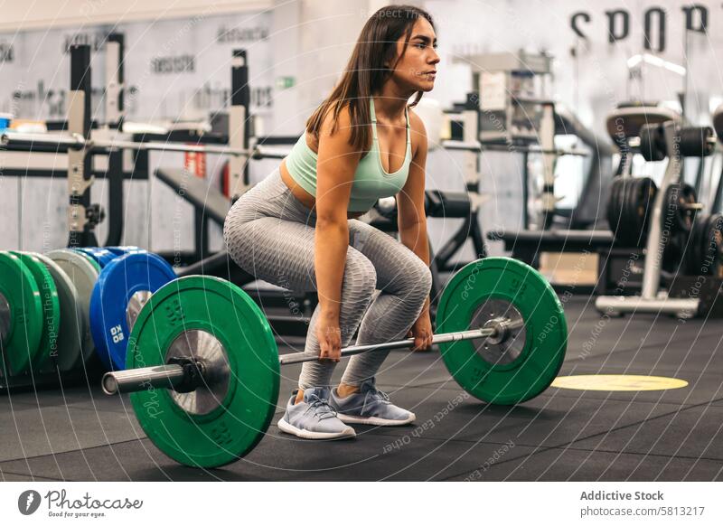 woman athlete doing deadlift in a gym. side view sport healthy fitness strength workout barbell strong people weight muscular body training female lifestyle