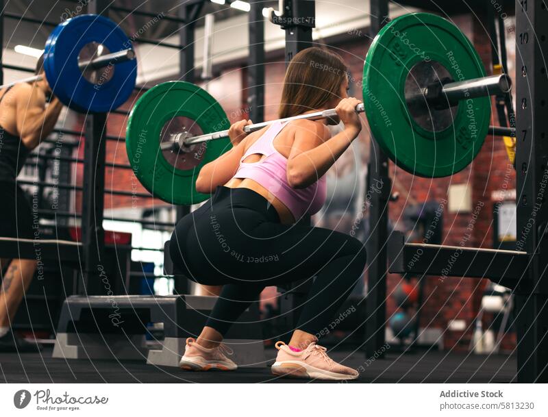 back view of a female athlete doing squats in a gym training exercise fitness workout young strong woman sport health sporty body strength healthy lifestyle