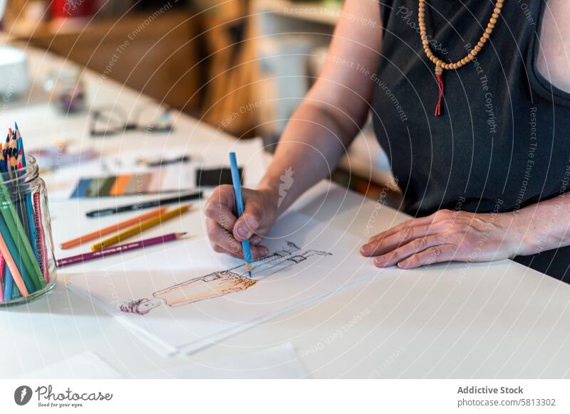 High angle of a fashion designer drawing a fashion sketch with colorful pencils 50s above clothing confidence confident creativity desk directly above