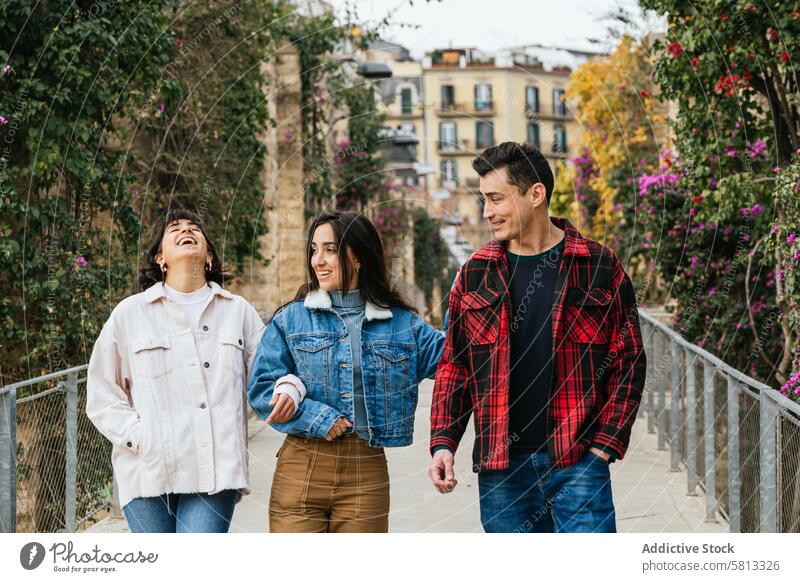 Friends enjoying a leisurely walk outdoors friends bridge laughter urban greenery casual clothing jeans jackets company togetherness bonding friendship young