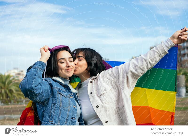 LGBTQ+ Friends Enjoying a Day Outdoors friendship lgbtq+ pride rainbow flag affection kiss cheek denim jacket love diversity inclusive happiness outdoor sky