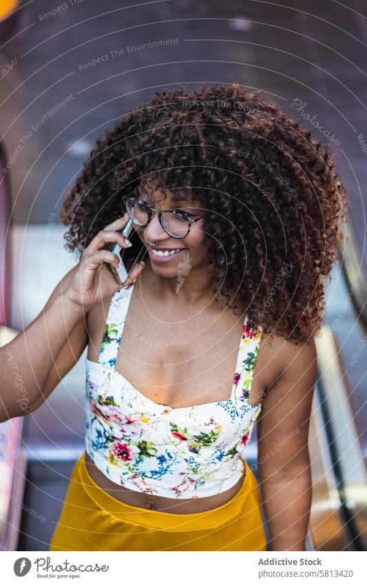 Glad African American woman speaking on smartphone in park smile summer style happy curly hair glasses female call talk cheerful gadget device conversation