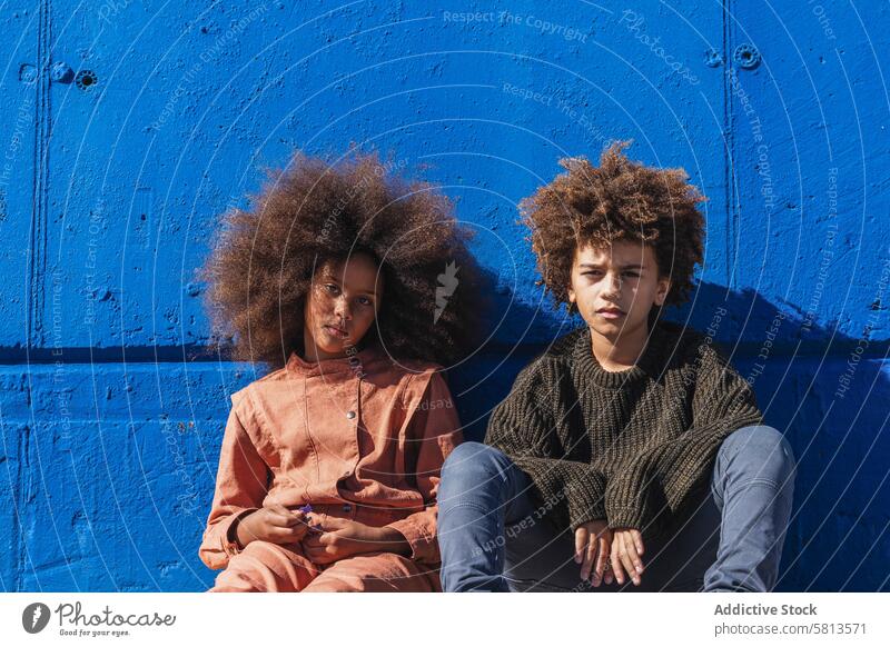 Black curly haired boy and girl resting near wall on street kid afro hipster together friend teen sibling african american black ethnic hairstyle lifestyle
