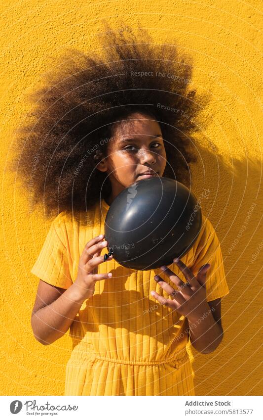 Black girl holding party balloon black yellow afro curly hair colorful vivid inflate child kid teenage hairstyle ethnic african american bright lifestyle female