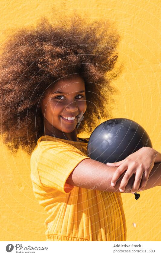Black girl holding party balloon black yellow afro curly hair colorful vivid inflate child kid teenage hairstyle ethnic african american bright lifestyle female