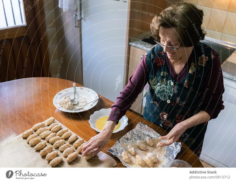 Aged woman preparing lots of handmade croquettes at home top view happy aged culinary homemade kitchen senior joyful process elderly family chef delicious