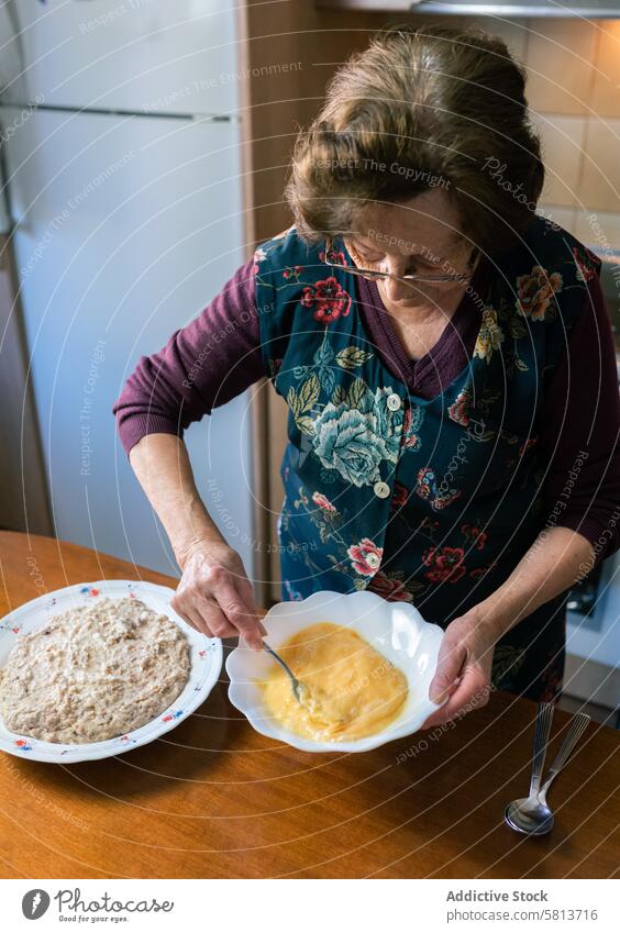 Aged woman beating eggs at home making handmade croquettes vertical aged mix ceramic stand patience love preparation kitchen senior culinary food homemade