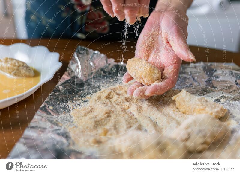 Senior woman coating croquettes with breadcrumbs at home close-up aged hands senior preparation kitchen homemade culinary food recipe cuisine elderly handmade