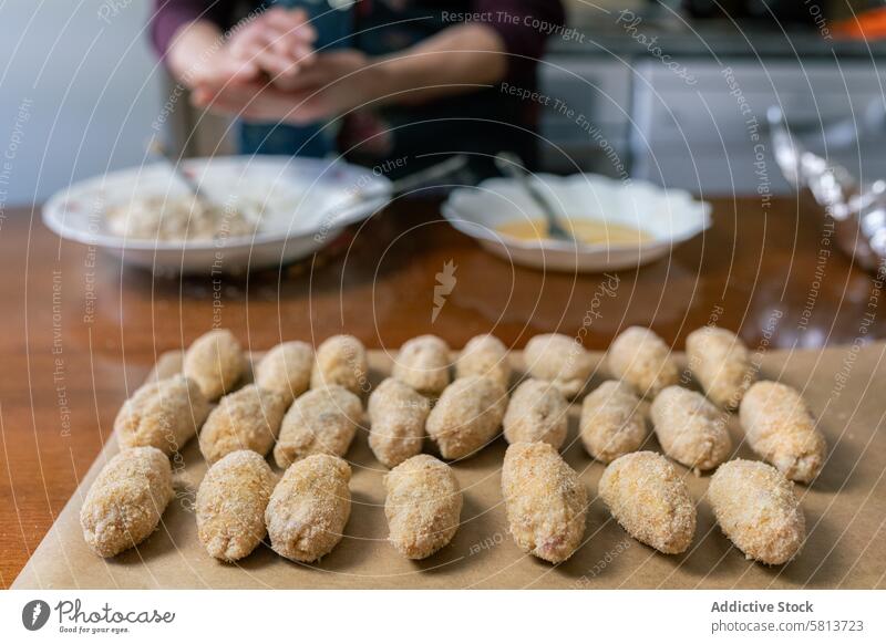 Many croquettes lined up and ready to fry senior woman preparing many cooking quantity culinary homemade kitchen process meal chef elderly food recipe cuisine