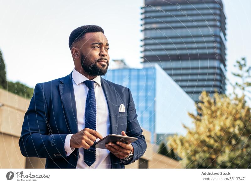 black businessman in a suit using a tablet outside. He looks concentrated meeting team professional executive success entrepreneur finance corporate