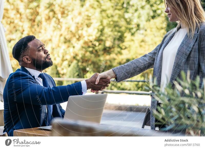 Business black man doing interview with laptop to a woman in outdoor cafe african american male business meeting team professional executive success
