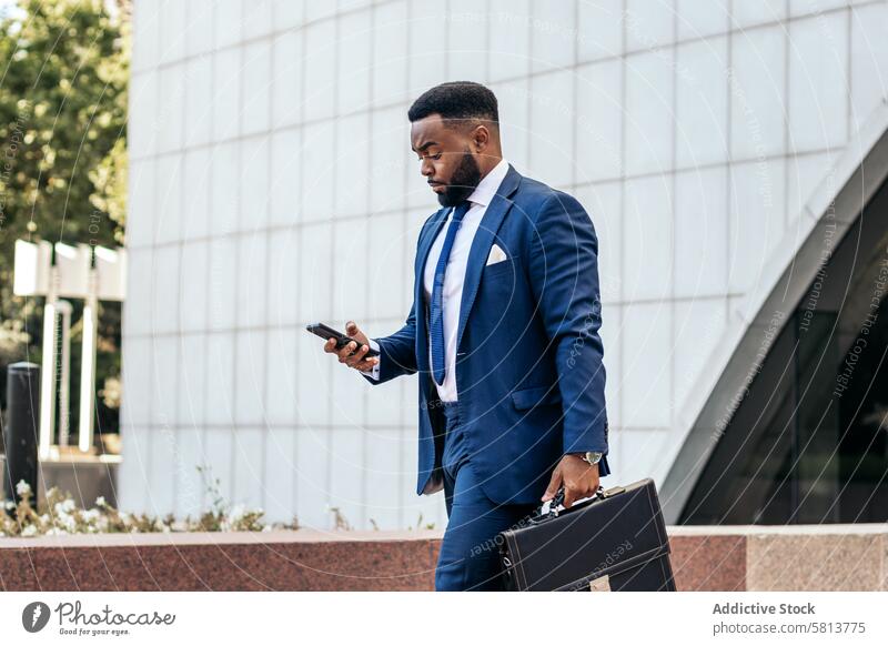 Business black man in suit leaving the office holding his work briefcase and using smartphone business meeting team professional executive success entrepreneur