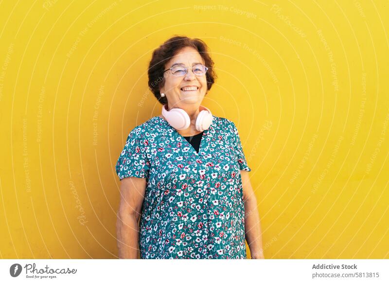 Portrait of an old woman in colorful clothes on yellow background stylish senior female lifestyle people businesswoman caucasian technology happy lady elder