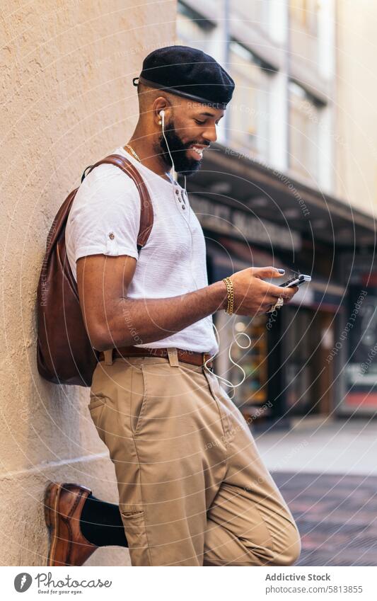 Stylish black man using smartphone and listening to music outdoors in the city technology lifestyle young street urban mobile male person cellphone stylish guy