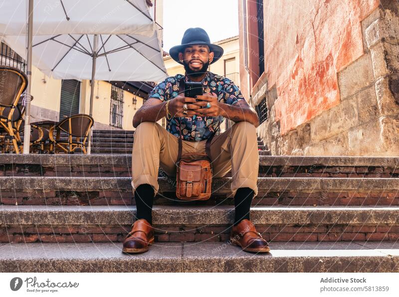 Stylish black man in the city street using smartphone technology lifestyle young urban mobile male person cellphone stylish guy outside people casual looking