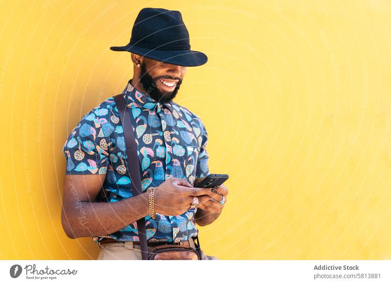 Stylish black man using smartphone outdoors over yellow background technology lifestyle city young street urban mobile male person cellphone stylish guy outside