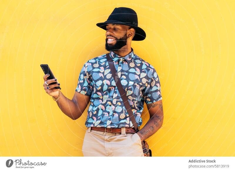 Stylish black man using smartphone outdoors over yellow background technology lifestyle city young street urban mobile male person cellphone stylish guy outside