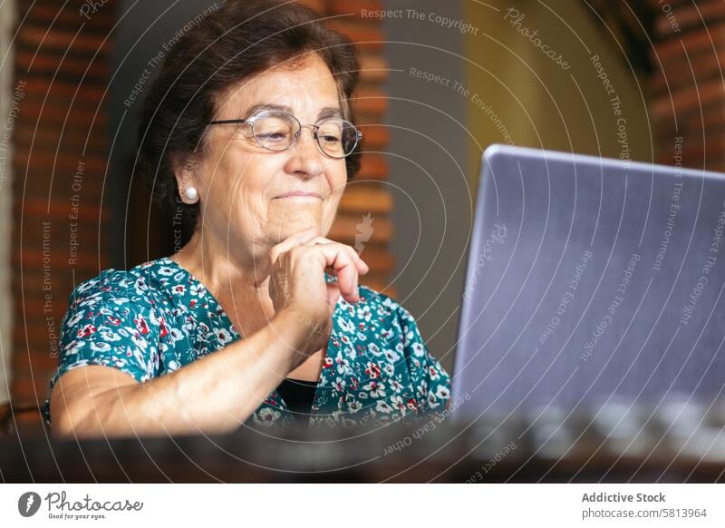 Senior woman with glasses using a laptop at home senior technology computer mature happy female internet person people sitting lifestyle adult smiling elderly