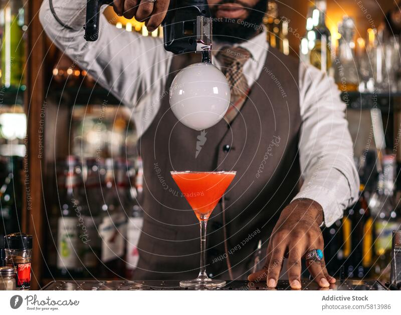 Stylish black bartender preparing a cocktail with a smoke bubble in a traditional cocktail bar barman beverage mixologist nightclub alcohol barkeeper glass