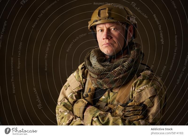 portrait of an airsoft soldier in camouflage clothing with arms crossed army military man armed war weapon combat special rifle helmet uniform person gun