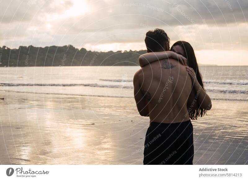 Young couple embracing on the beach at sunset love together man romance happy people young two ocean romantic female vacation lovers relationship kiss sea woman