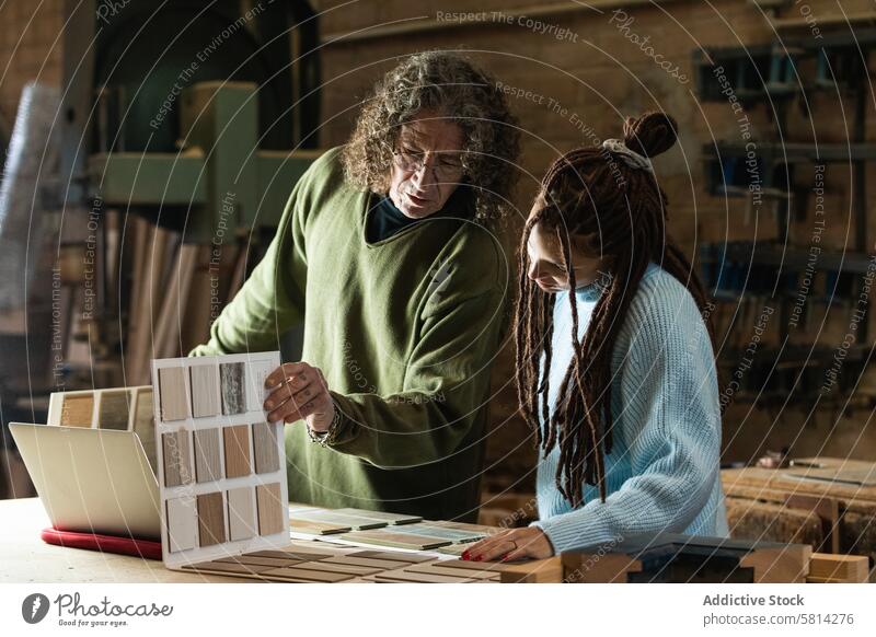 Woman choosing sample with carpenter in workshop woman artisan client choose order help joinery workbench female pick craftsman job industry manufacture busy