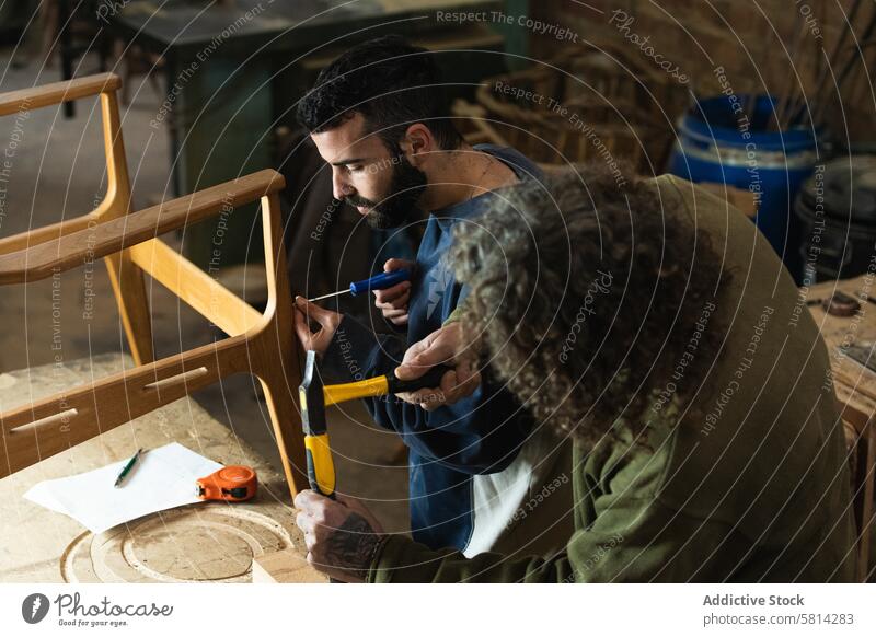 Male artisans creating wooden furniture in workshop men carpenter colleague hammer screwdriver joinery chair woodwork male carpentry craft concentrate workplace