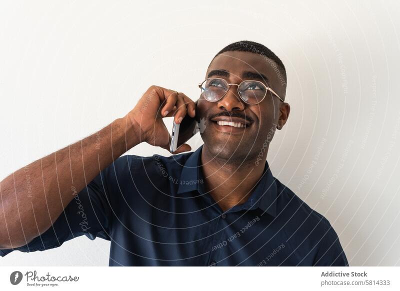 Black guy with phone near white wall man smartphone well dressed modern smile happy glad eyeglasses studio shot netbook black african american male adult shirt