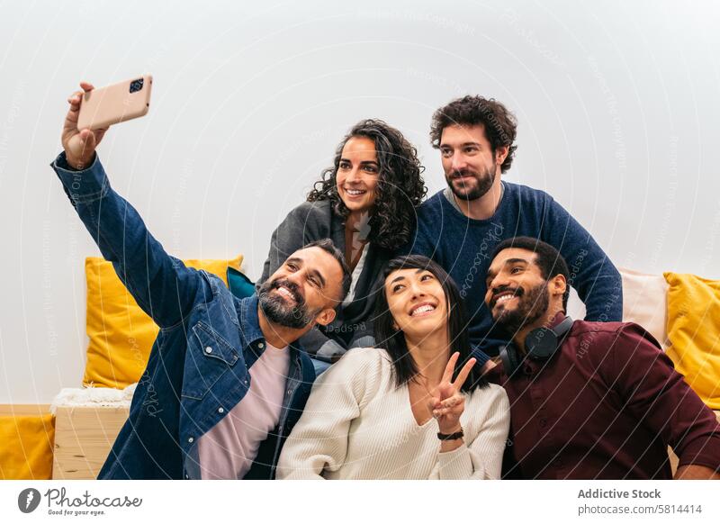 Multiracial happy coworkers taking a selfie with smartphone in the break room of a modern coworking office startup modern workspace ethnicity diversity business