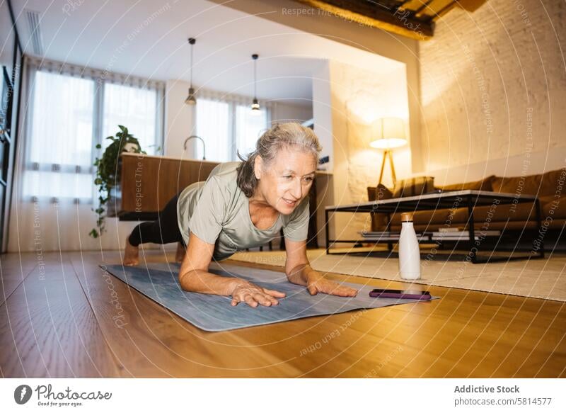Senior Woman doing yoga at home 65-69 years One senior woman only active active seniors adult aged alone body care body conscious body positive domestic life