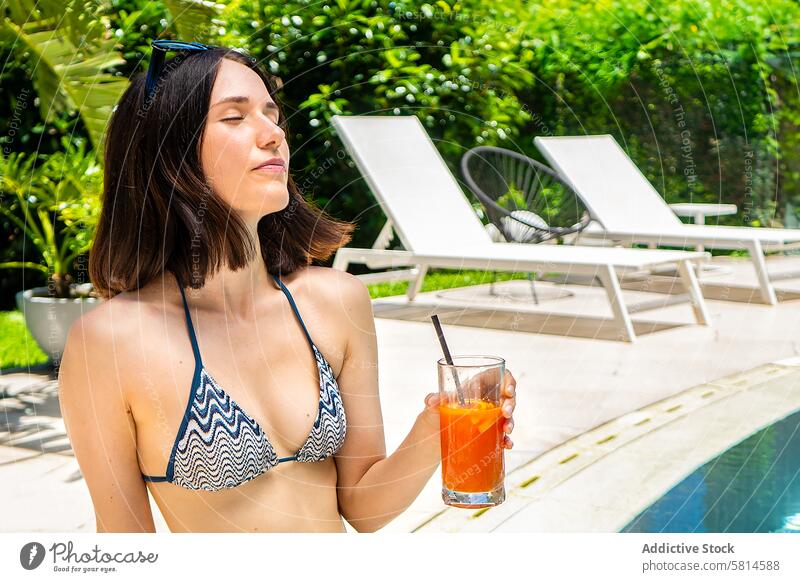 Beatiful woman relaxing by the pool  with a juice in her hand. adult attractive beautiful beauty beverage bikini carefree caucasian chair charming cocktails