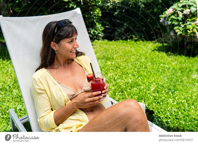Beatiful woman relaxing on a lounge chair with a juice in her hand. adult attractive beautiful beauty beverage bikini carefree caucasian charming cocktails