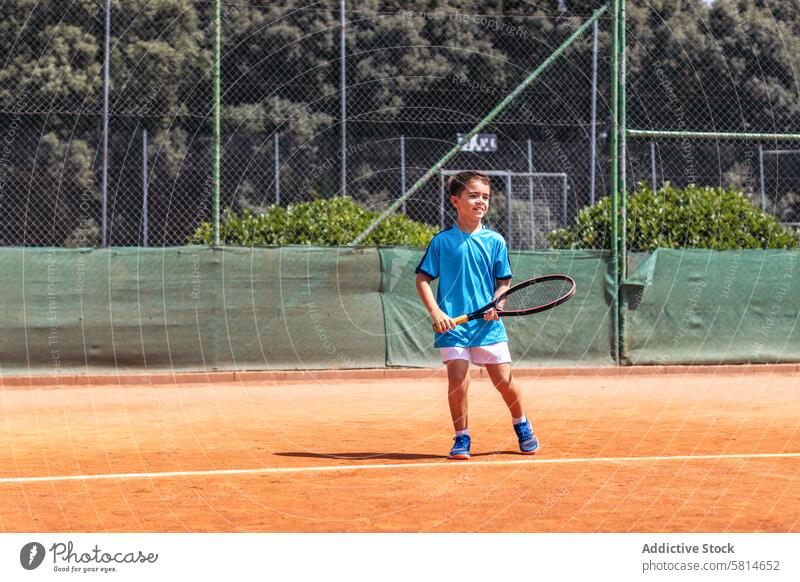 Little boy playing tennis on a dirt court activity sport game racket child person player kid athlete training lifestyle childhood healthy exercise ball happy
