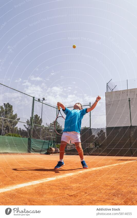 Little boy playing tennis on a dirt court making a serve activity sport game racket child person player kid athlete training lifestyle childhood healthy