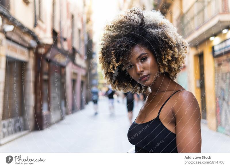 Black woman standing on street looking at camera serious urban millennial posture female beautiful building casual attractive brunette long hair hairstyle