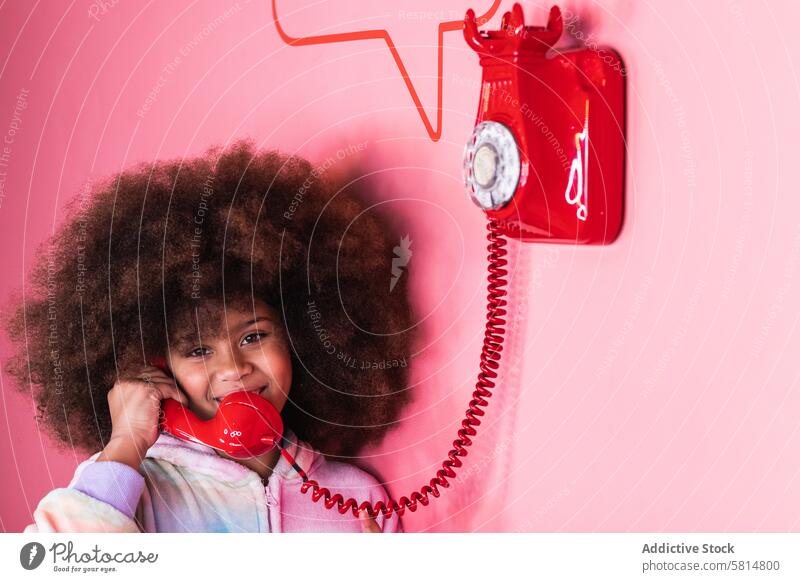 Black girl speaking on telephone in studio old fashioned talk smile child retro red ethnic black african american afro hairstyle cheerful call communicate joy