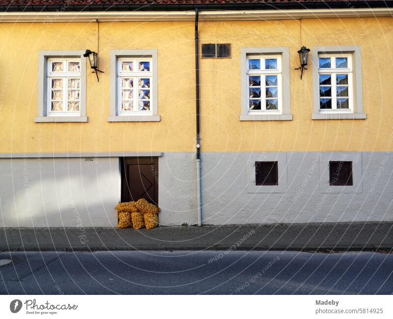 Potato sack in front of the old cellar door of a listed old building with a façade in beige and natural colors with lattice windows in Oerlinghausen on Hermannsweg in the Teutoburg Forest in East Westphalia-Lippe