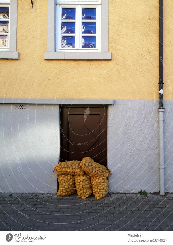 Potato sack in front of the old cellar door of a listed old building with a façade in beige and natural colors with lattice windows in Oerlinghausen on Hermannsweg in the Teutoburg Forest in East Westphalia-Lippe