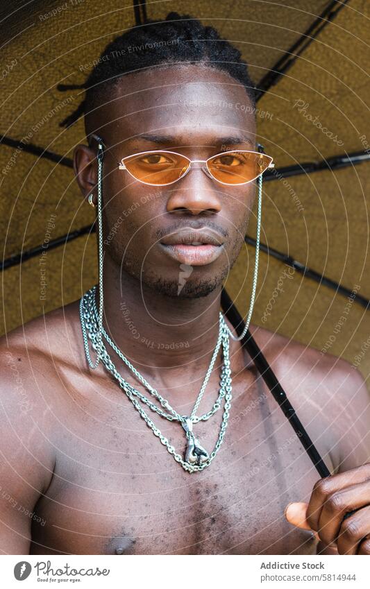Stylish shirtless black man with umbrella sunglasses style trendy accessory fashion serious portrait confident ethnic young african american naked torso chain
