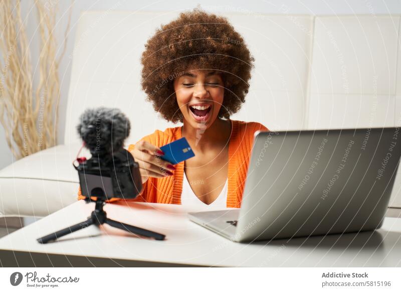 young latina woman with afro hair happy to shop online with laptop and pay by credit card while shopping paying technology female computer person home lifestyle