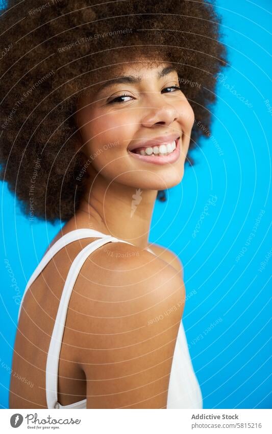portrait of a latina woman with afro hair smiling studio photo with blue background female model beauty person young expression adult black face fashionable