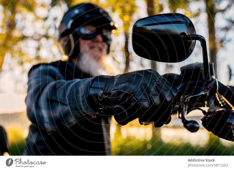 Senior biker enjoying a motorcycle ride at sunset senior man mature beard helmet goggles handlebar gloves leisure outdoor leather activity adventure travel