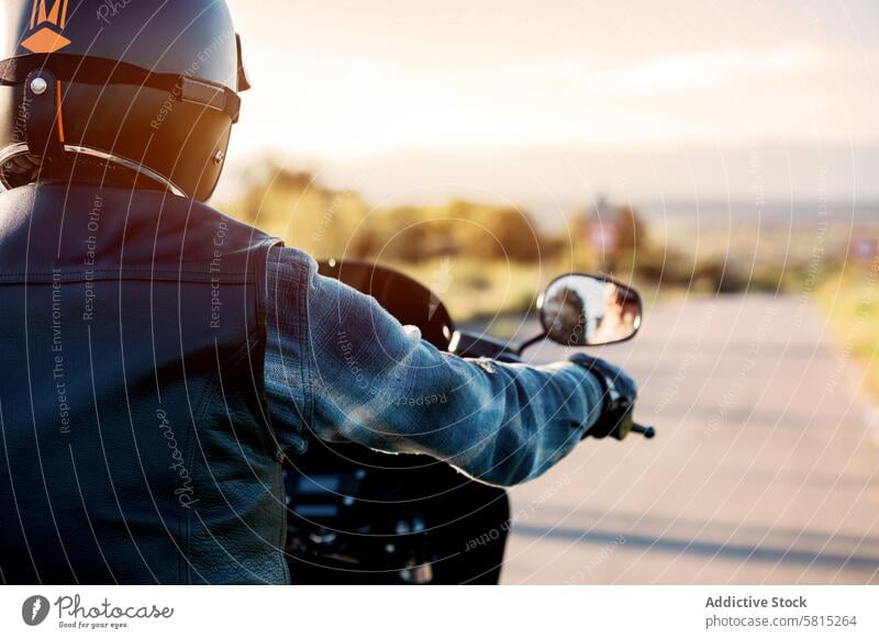 Biker enjoying a sunset ride on country road biker motorcycle leather jacket helmet looking away leisure recreation transportation motorbike hobby lifestyle
