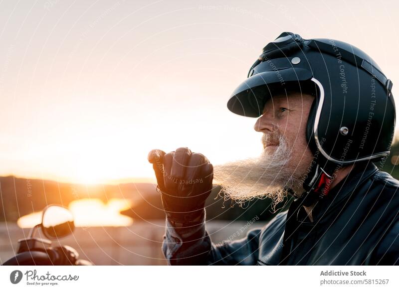 Senior biker with helmet enjoying sunset ride senior motorcycle male elderly freedom scenic adventure serene retirement motorcyclist looking away road trip